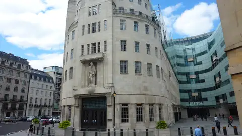 The curved Portland stone front of BBC Broadcasting House in London beside its newer glass extension