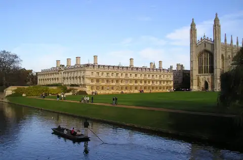 Clare College and King's College Chapel seen across the lawn from the river, with a punt on the water