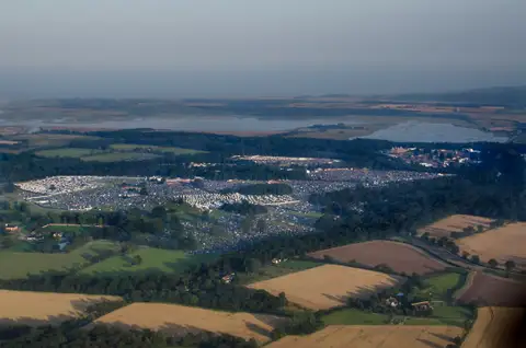 Aerial view of a festival site of tents and stages among fields and woodland in Suffolk